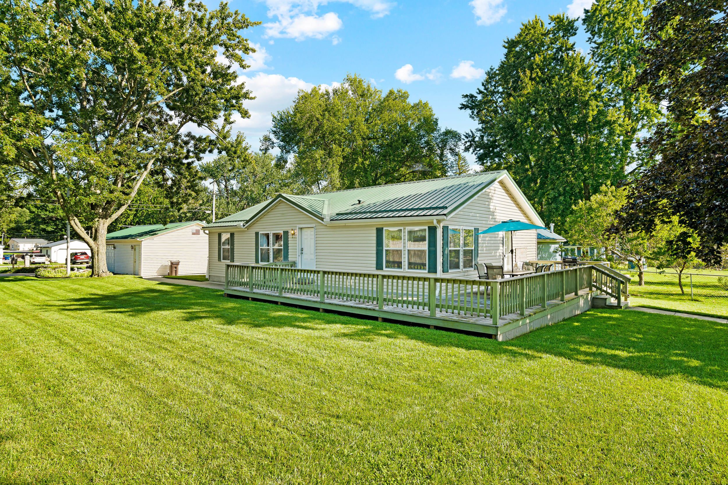 A single-story house with a porch, a covered outdoor seating area, and a well-maintained lawn.