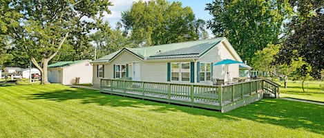 A single-story house with a porch, a covered outdoor seating area, and a well-maintained lawn.
