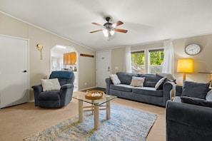 A living room with a ceiling fan, a sofa, a coffee table, and a lamp.