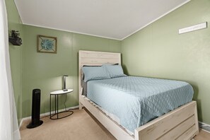 A bedroom with a bed, a bedside table, a lamp, and a radiator. - Lake Escape Cottage | Lake Access w/ Fire Pit! (Coldwater)