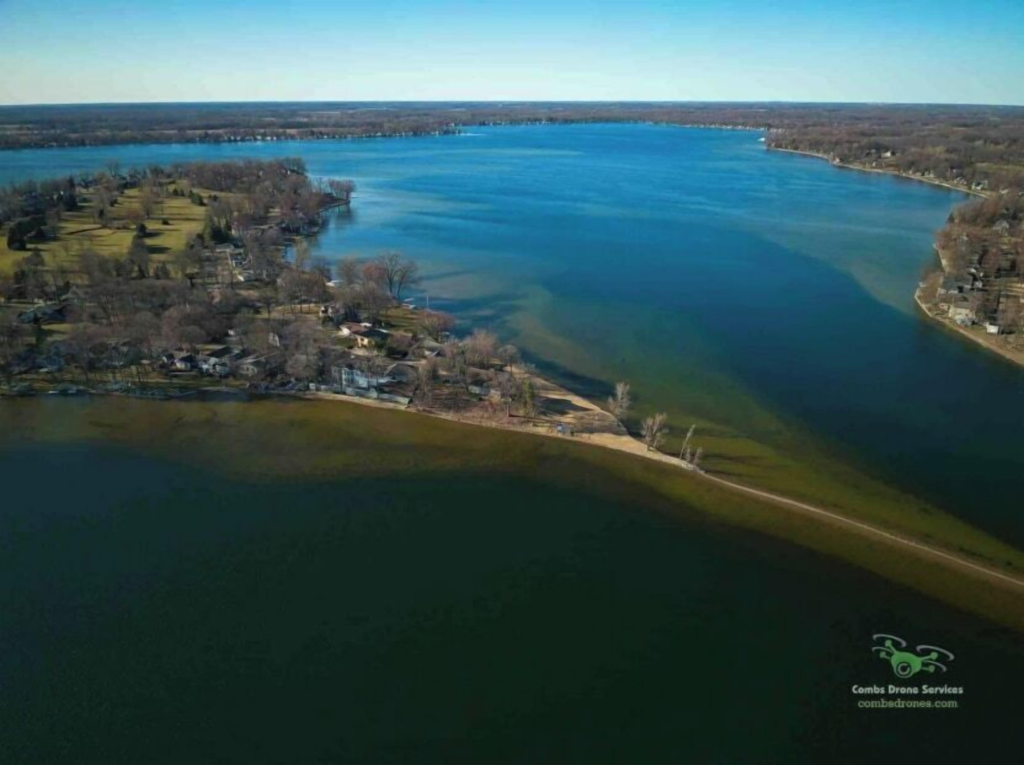 Une vue aérienne d’un lac, avec une petite ville sur une rive et une jetée qui s’avance dans l’eau.