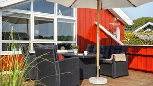 An outdoor seating area with wicker furniture, a table, and a large umbrella. - Nice home in Tarm with sauna (Tarm)
