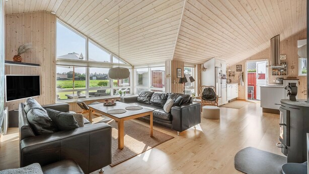 A spacious living area with a high ceiling, large windows, a modern kitchen, and a cozy seating arrangement. - Nice home in Tarm with sauna (Tarm)