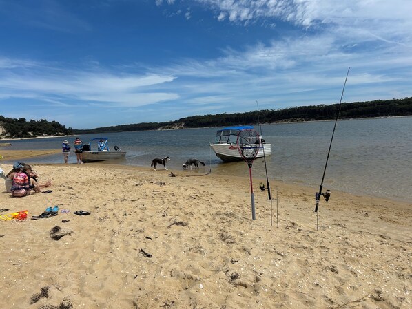 A beach with boats, fishing rods, and people.