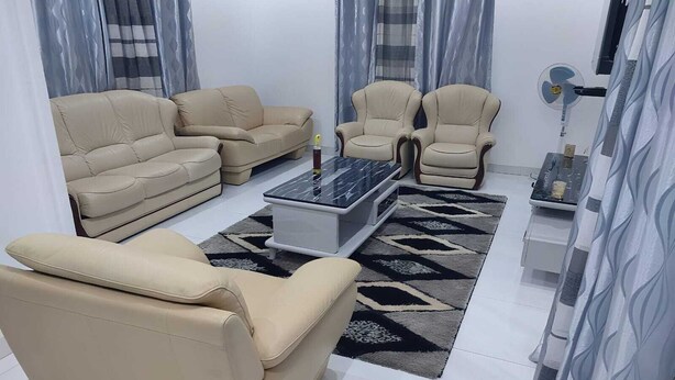 Een moderne woonkamer met beige banken, een glazen salontafel en kamerbreed tapijt.