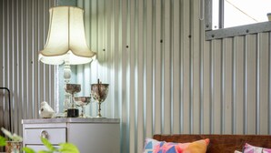Un banc en bois agrémenté de coussins colorés, une plante en pot et une lampe posée sur une table.