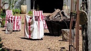 Une entrée rustique, agrémentée d’une arche en métal, d’une enseigne indiquant « dépôt de chariots » et d’une pile de bois de chauffage.