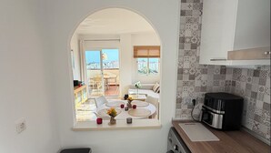 Cocina compacta con vistas a un área de estar exterior, lavadora y estufa pequeña.
