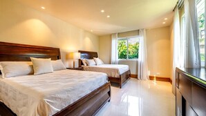 Habitación de hotel con dos camas, una mesita de noche, un televisor y una ventana con cortinas.