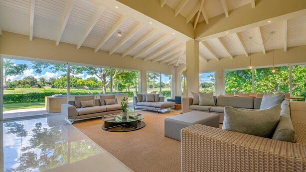 Amplia sala de estar con grandes ventanales, un techo alto y vistas a un jardín exuberante.