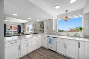A modern kitchen with white cabinetry, a large window, and a view of the city. - The Ultimate Beach Getaway for Large Groups! (Redington Shores)