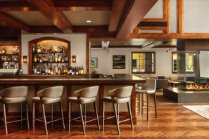 A bar area with a wooden bar, multiple stools, and a variety of bottles. - The Ritz-Carlton, Vail-Charming 2BRM/2.5BATH Mountain Suite With Balcony (Vail)