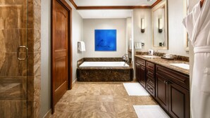 Un baño moderno con piso de mármol, una bañera grande y un tocador con lavamanos.
