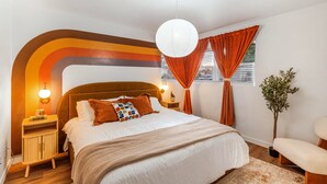 Un dormitorio moderno con una cama grande, una mesita de noche, una lámpara y vistas al exterior por la ventana.
