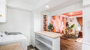 Una cocina moderna con armarios blancos, encimera de madera y un comedor con mesa y sillas.