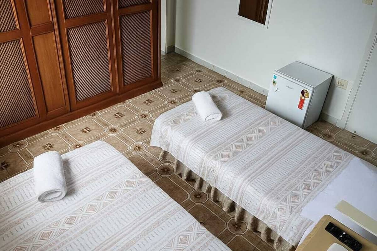 A room with two beds, a TV, a heater, and a window.