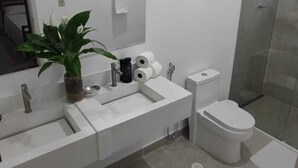 Casa de banho moderna com lavatório duplo, sanita e cabine de duche em vidro.