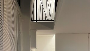A narrow hallway with a wooden staircase leading to a door. Shelves with decorative items line one wall. - Green House Sea (Bisceglie)