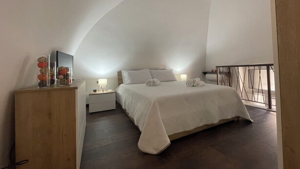 A bedroom with a large bed, a nightstand, a dresser, and a TV. - Green House Sea (Bisceglie)