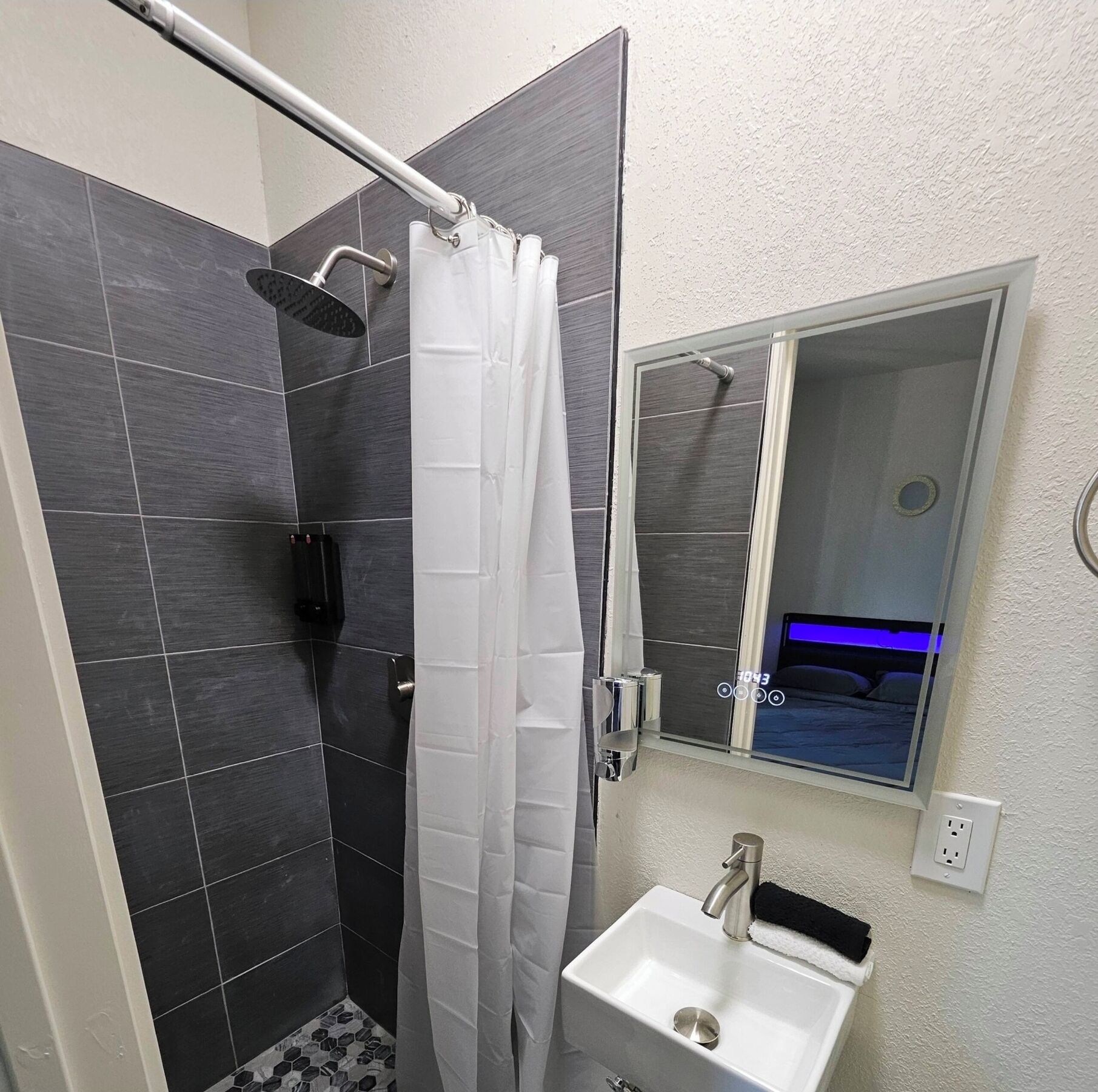 A bathroom with a shower, a sink, and a mirror.