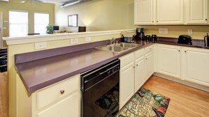 A compact kitchen with white cabinets, a dishwasher, and a coffee maker. - Charming Townhouse in Louisville – Explore the Urban Oasis! (Louisville)