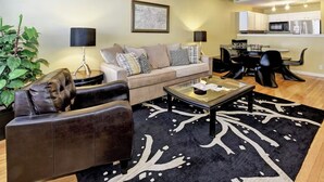 A living room with a sofa, coffee table, and a dining area with chairs and a table. - Charming Townhouse in Louisville – Explore the Urban Oasis! (Louisville)