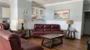 A living room with a leather sofa, a wooden coffee table, and two lamps. - Gulf View - 3 bed/3.5 bath Cape San Blas FL. Pet friendly! (Port St. Joe)