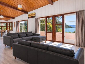 Een ruime woonkamer met een grote hoekbank, houten balken in het plafond en een bord met de tekst 'Champlure Grain and Fooder'.