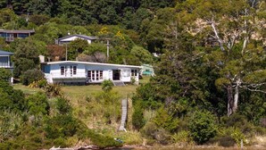 A house with a front porch, a small deck, and a staircase leading to a garage. - Waterfront Marlborough Sounds Retreat 10min drive from Picton (Whatamango Bay)