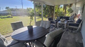 Un patio techado con una mesa redonda y sillas, un sofá y una mesa de centro.