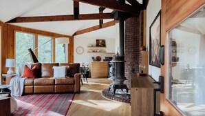 A cozy living room with a brown leather sofa, a red and white patterned rug, and a large window. - THE Treehouse, Panoramic Views, Coffee Bar, KING Bed (Cascade-Chipita Park)