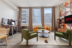 A modern living room with a sofa, chairs, a coffee table, and a TV displaying 'NETFLIX'. - Indy City Views - Walk to Stadium + Arcades (Indianapolis)
