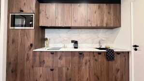 A modern kitchen with wooden cabinets, a built-in microwave, a marble backsplash, and a stainless steel sink. - The suite - Cosy hotel room ambience. Pets welcome! (Orléans)