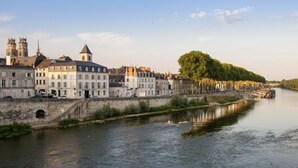 A river with buildings along the banks, a bridge in the distance, and a tree-lined path. - The suite - Cosy hotel room ambience. Pets welcome! (Orléans)