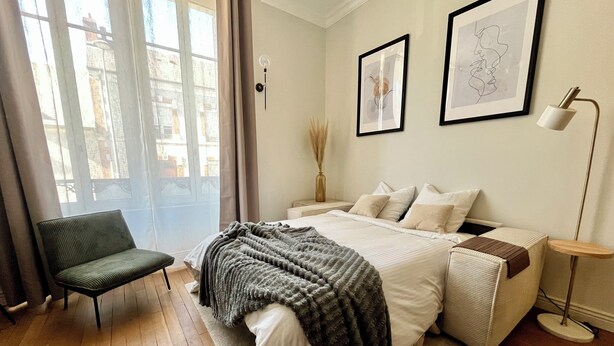 A bedroom with a large bed, a chair, a bedside table, and a floor lamp. - The suite - Cosy hotel room ambience. Pets welcome! (Orléans)