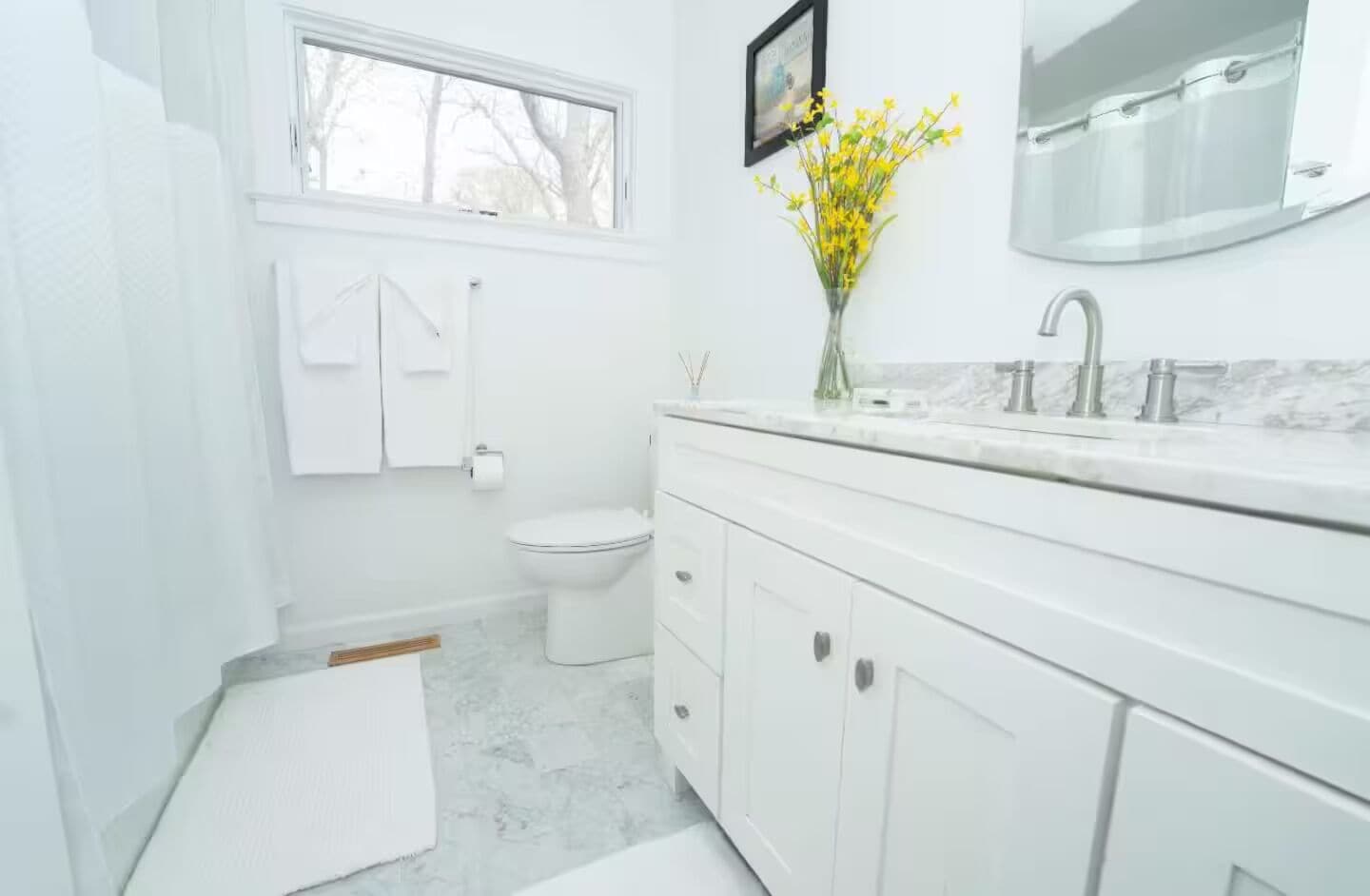 Un baño moderno con inodoro, lavamanos y espejo.