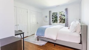 Un dormitorio con una cama, un escritorio y una ventana con cortinas.