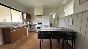 Cocina compacta con comedor, que incluye una mesa, sillas, microondas, estufa y armarios.