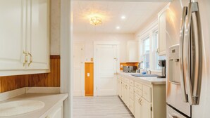 Una cocina moderna con armarios blancos, un refrigerador de acero inoxidable y piso de madera.
