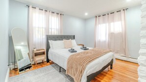 Un dormitorio con cama, mesitas de noche, un espejo y cortinas.