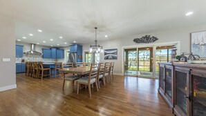 A spacious kitchen with wooden cabinets, a dining area with a table and chairs, and a large window offering a view of the outdoors.