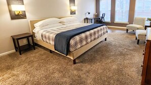 A bedroom with a bed, a ceiling fan, two bedside lamps, a chair, and a desk. - Enchanting 2-bedroom, Sleeps 6, in Heart of Highlands-Nulu-Bardstown Road (Louisville)