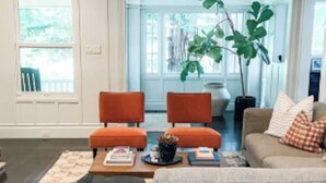 A living room with a grey sofa, two orange chairs, a coffee table, and a patterned rug. - Central Marin Living - 3 Bedroom House in Corte Madera (Corte Madera)