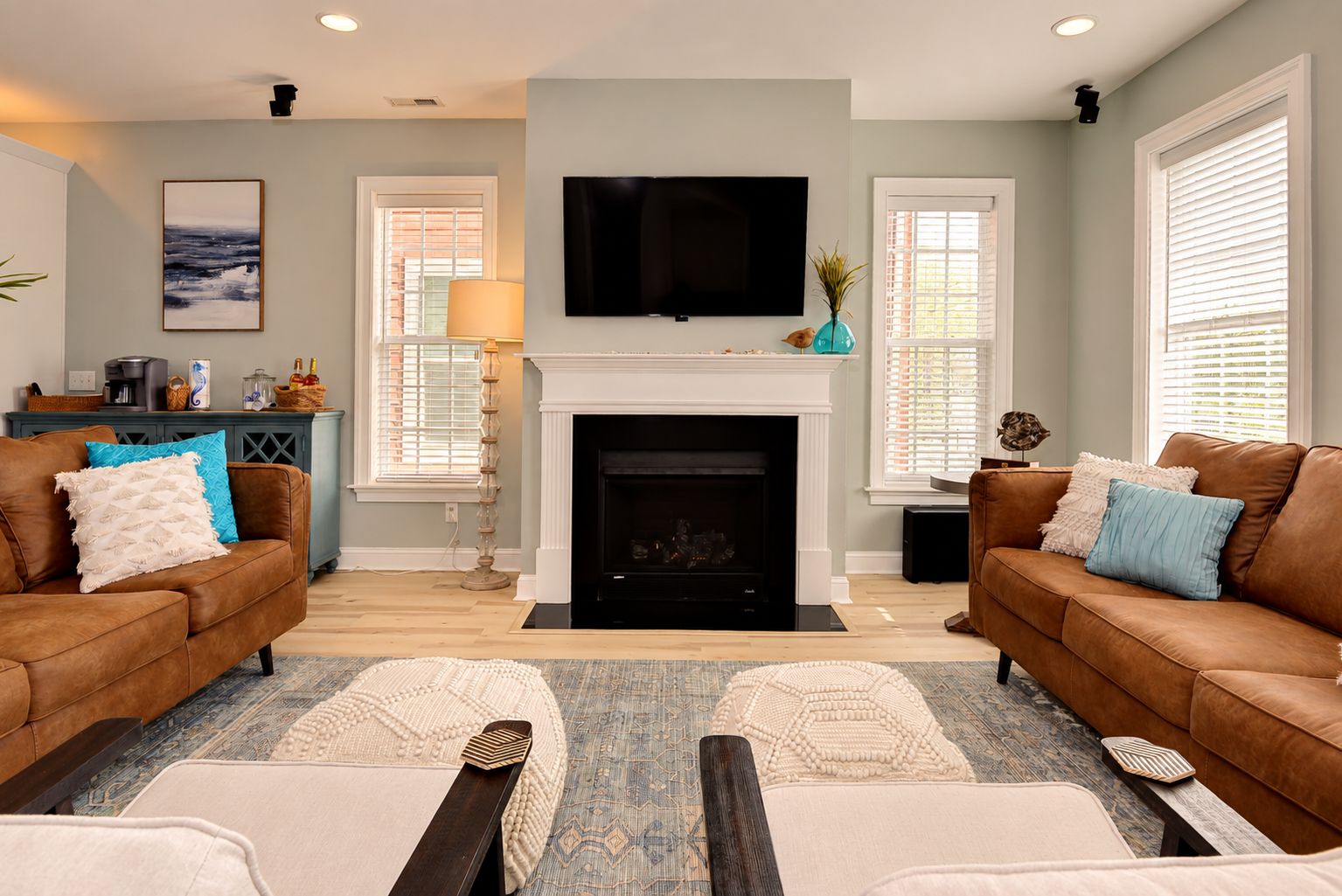 A living room with two brown leather sofas, a fireplace, a flat-screen TV, and a coffee table.