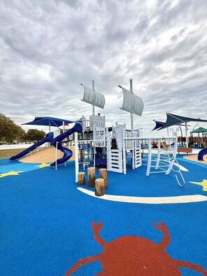 A playground with slides, climbing structures, and a crab design on the ground.