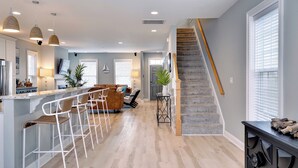 Una cocina moderna con barra, suelo de madera y una escalera que sube a otro nivel.