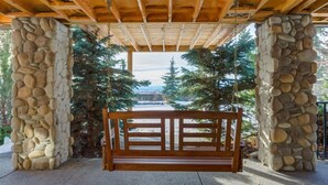 Une structure composée de piliers en pierre, avec un banc en bois au centre, le tout entouré d’arbres.