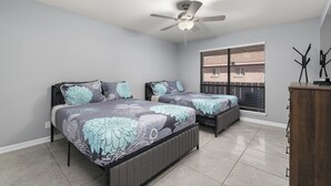 Un dormitorio con dos camas, un ventilador de techo, una ventana con persianas y un armario de madera.