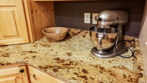 A kitchen with wooden cabinets, a granite countertop, a mixer, and a wooden bowl. - Moose Mountain Lodge Above Park City (Summit County)