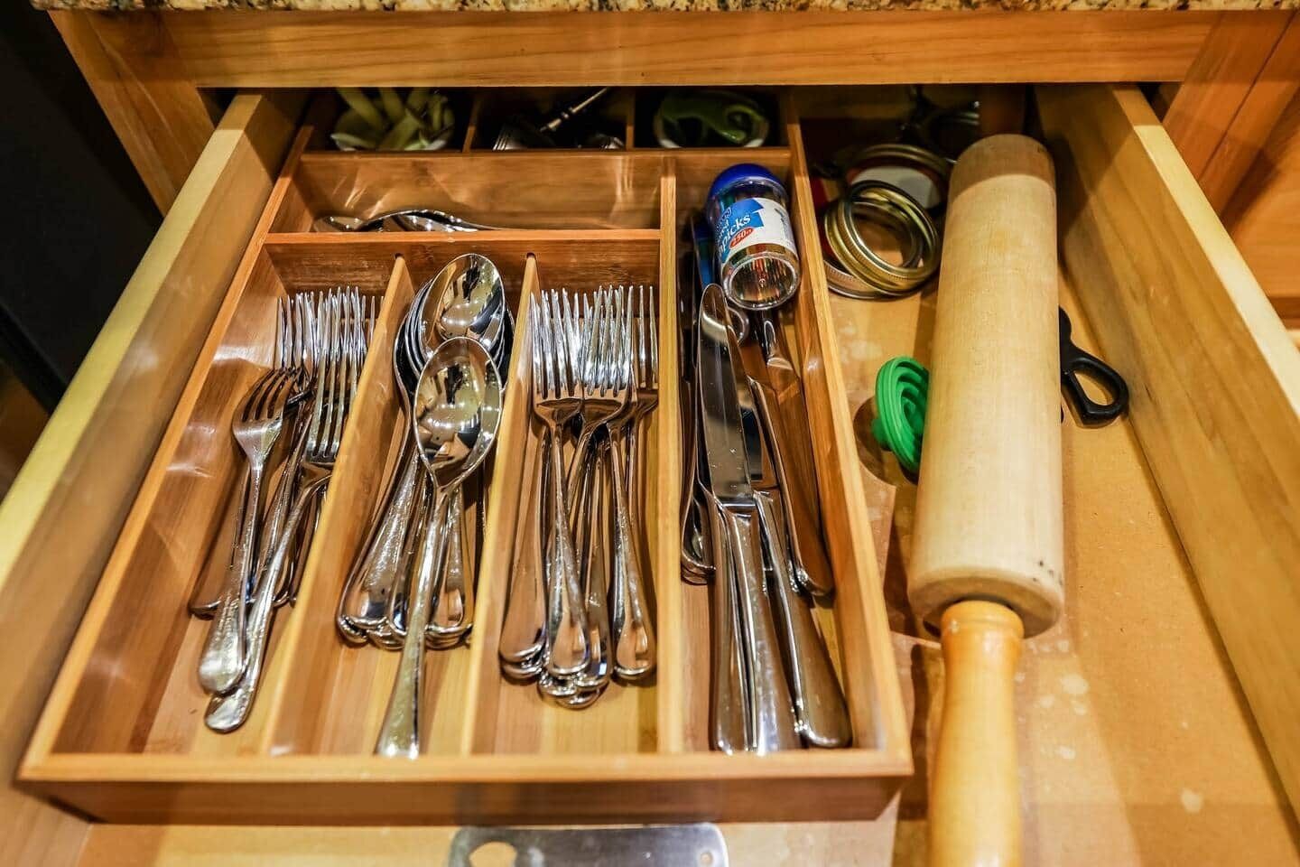 A drawer with neatly organized silverware, including forks, spoons, and knives.